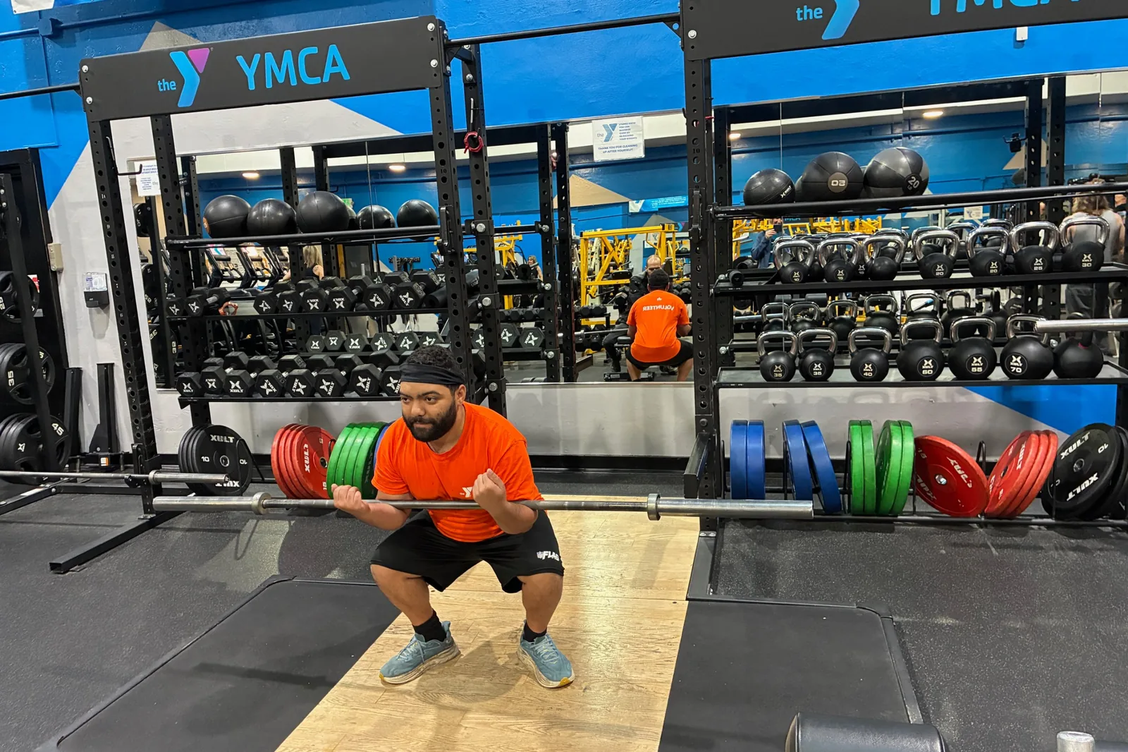 Louie Speice demonstrates a front squat with a barbell on a lifting platform at the Medford YMCA.