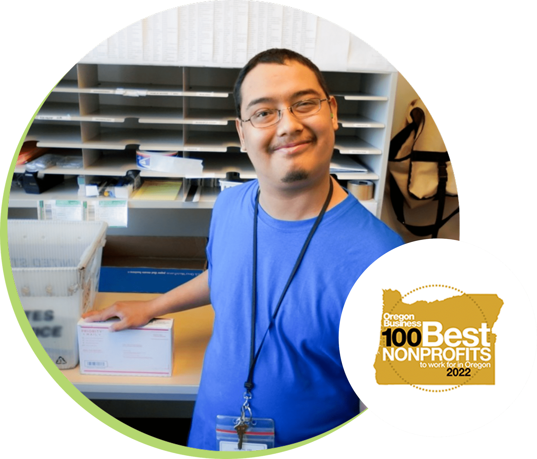 Worker wearing a blue shirt and lanyard in a mailroom smiling.